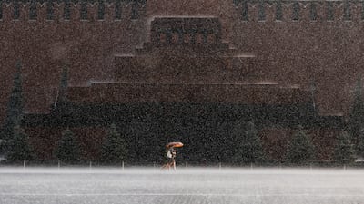 People walk by Lenin's Mausoleum during heavy rain in Red Square, Moscow. Reuters
