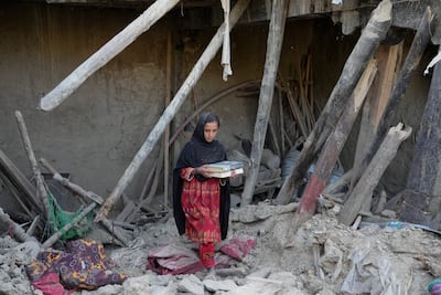 An Afghan girl salvages belongings from her destroyed house after an earthquake in Gayan district in Paktika province, in Afghanistan, on June 26. AP