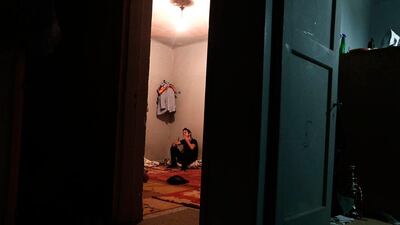 An immigrant smokes a cigarette inside an apartment.