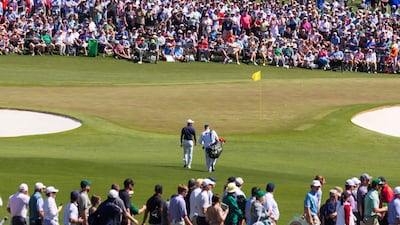 Tiger Woods and his caddie Joe LaCava walk onto the second green surrounded by fans. EPA