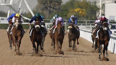 Jockey Sam Hitchcott on his One Man Band (R) leads before winning the Godolphin race during the Dubai World Cup day horse racing event on March 26, 2016 at the Meydan racecourse in the United Arab Emirate of Dubai. Closing the UAE racing season, the Dubai World Cup day features nine races including the world’s richest horse race, the ten million US dollars Dubai World Cup. / AFP / KARIM SAHIB