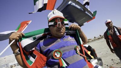 Two enterprising traders set up a stall from the boot of their car to sell National Day flags, scarves and rosettes – and business was booming yesterday. Jaime Puebla / The National