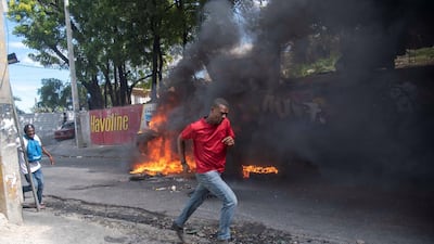 A person runs pass a burning blockade during a protest in Port-au-Prince. EPA