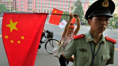 A woman waves a Chinese flag behind a Chinese member of security as he stands guard during the Olympic torch relay ceremony near the Tiananmen Square in Beijing.