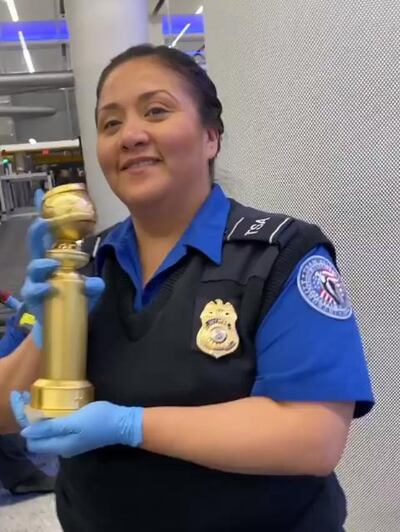 A TSA agent holds Ramy Youssef's Golden Globe award at the airport. Ramy Youssef / Instagram