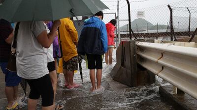People play with overflown water caused by Typhoon Nida in Hong Kong, Tuesday. The Hong Kong Observatory issued the number 8 storm signal, as Typhoon Nida moved northwest across southern China, bringing high winds and heavy rain but no immediate reports of deaths or destruction. Kin Cheung / AP