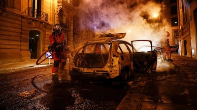 Firefighters extinguish a burning car near the Champs-Elysees in Paris. AFP