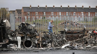 A man walks past a destroyed bus on Shankill Road in Belfast after violence in April. AP