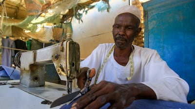 A displaced Sudanese tailor cuts textiles at his workshop at the Abu Shouk camp for internally displaced persons, 20 km north of El-Fasher, the capital of the North Darfur state. AFP