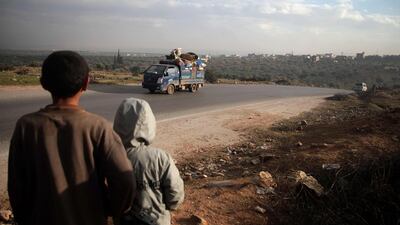 Syrian boys watch belongings being loaded on trucks in Al Mastumah, south of the city of Idlib, as families flee the government assault. Aaref Watad / AFP