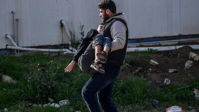 A man carries an injured man after a rocket hit a road in the Reyhanli district in Hatay province, near the Turkey-Syria border, on January 31, 2018.AFP PHOTO / OZAN KOSE