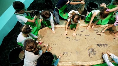 Children take part in the "dig a dinosaur" activity at the Abu Dhabi Science Festival at Mushrif Central Park. (Christopher Pike / The National)