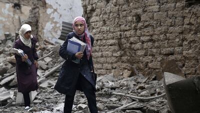 Young Syrian women carry books as they walk amid the rubble of destroyed buildings following a reported air strike by Syrian government forces in the rebel-held area of Douma, east of the capital Damascus, on October 29, 2015. AFP PHOTO / SAMEER AL-DOUMY