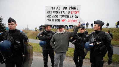 A protestor holds a poster reading "Emmanuel, we made an effort, we crossed the street to tell you, go away" before French President Emmanuel Macron's visit in Grand Bourgtheroulde, Normandy. AP