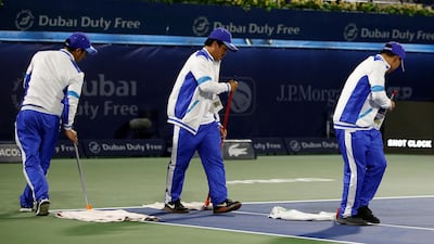 Workers wipe the court during a rain break. EPA
