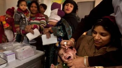 An Indian boy tries to avoid the dropper as he is held by his mother while a health worker administers a polio drop during a routine vaccination in New Delhi Friday.