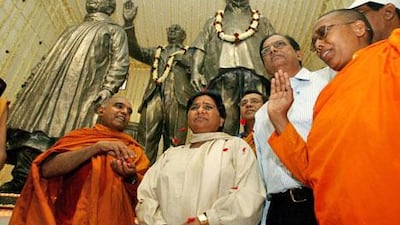 Kumari Mayawati, the chief minister of Uttar Pradash, centre, stands in front of a statue of herself. The Election Commission ruled that she must cover statues because it will give her an unfair advantage with voters.