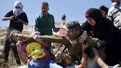 The Israeli soldier pushes the Palestinian girl after she bites him. Abbas Momani / AFP Photo