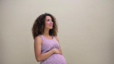 A pregnant woman holds her bump feeling positive on a clean background. (Getty Images)