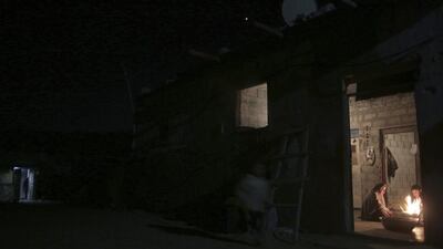 A Palestinian family warm themselves with a fire inside their makeshift home, during a power cut in a poor neighborhood in Khan Younis, southern Gaza Strip. Khalil Hamra / AP Photo
