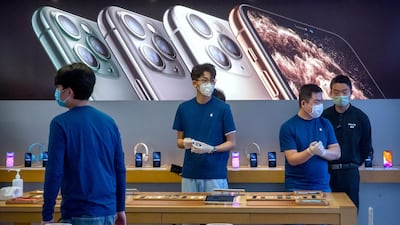 Employees wear face masks as they stand in a reopened Apple Store in Beijing. AP