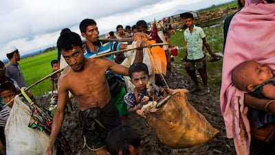 A Rohingya ethnic minority refugee from Myanmar carrying a child in a sack and walking through rice fields after crossing over to the Bangladesh side of the border near Cox's Bazar's Teknaf area, on September 1, 2017. Thousands of Rohingya have fled across the border in the past week amid recent violence in the western state of Rakhine triggered by attacks on security forces by insurgents from the Rohingya. Bernat Armangue/AP Photo