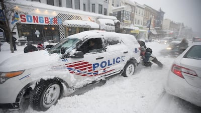 People pitch in to get a DC Metro police car moving again on 18th Street NW, Saturday, in Washington. Alex Brandon / AP