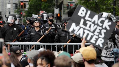 Police officers behind a barricade look on as protesters fill the street in front of Seattle City Hall. AP Photo