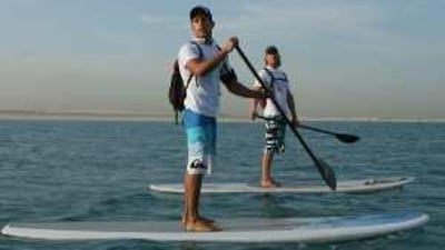Scott Chambers, left, and Daniel Van Dooren paddle surf around the World islands in Dubai to raise money for Indonesia.