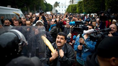 A Tunisian protester holding a baguette talks to riot policemen during a demonstration in Tunis on January 18, 2011. AFP