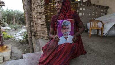 Shobha Singh Bais poses for photograph as she holds her husband's photograph works outside her house in Yavatmal, India, on Tuesday Feb. 3, 2015. Photographer: Dhiraj Singh/Bloomberg