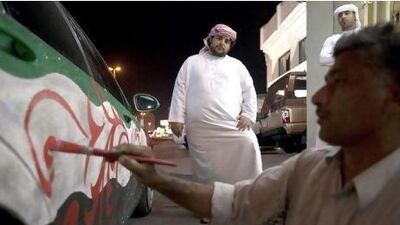 Ali Abdullatef of Abu Dhabi watches as an Emirates Arts employee paints his car for the National Day celebrations in Ras al Khaimah.