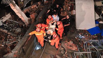 Rescuers carry an injured person from a collapsed factory building on July 4, 2015 in Wenling, China. The collapse of the shoe factory in Folong Village, Wenling City collapsed killed at least 12 people. Photo by ChinaFotoPress/Getty Images