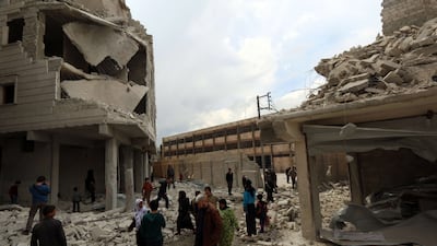 People walk past debris next to the Saad Ansari school (background) in the northern city of Aleppo, after it was destroyed by a Syrian regime air strike (AFP PHOTO / AMC / ZEIN AL-RIFAI)