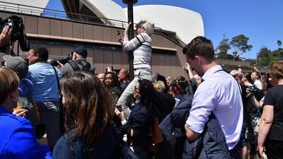 A royal fan climbs a lamppost to get a glimpse of Prince Harry and Meghan as they conduct a meet the people walk at the Sydney Opera House. EPA