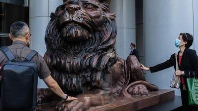 People touch a statue of a lion in front of the HSBC Holdings Plc headquarters building in Hong Kong. Bloomberg
