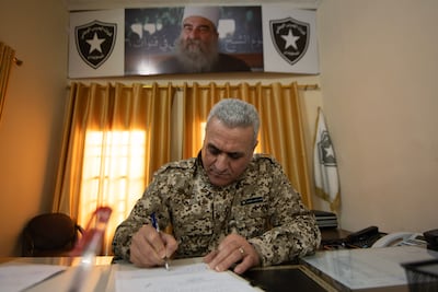 Brig Gen Jihad Ghoutani, of the National Guard in Sweida, in his office with a photograph of Druze cleric Sheikh Hikmat Al Hijri in the background. Hasan Belal for The National