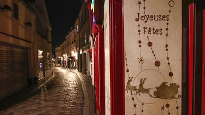 A placard is pictured in an empty street at Montmartre that reads "Happy Holidays' during the new imposed curfew in Paris. AP