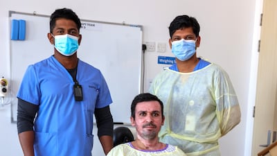 Gul Dad Dahri with hospital staff members Ajesh Babu, left, and Mr Mony