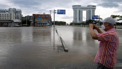 A man takes photos of a street flooded by Typhoon Maysak in Gangneung. AFP