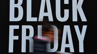 Shoppers pass a promotional sign for 'Black Friday' sales discounts in London. Black Friday is a sales offer originating from the US where retailers slash prices on the day after the Thanksgiving holiday. In the UK it is used as a marketing device to entice Christmas shoppers with the discounts at stores often lasting for a week. AFP