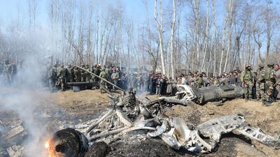 Indian soldiers and Kashmiri onlookers stand near the remains of an Indian Air Force aircraft after it crashed in Budgam district, 30 km from Srinagar. AFP