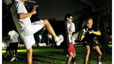 Phil Perrin, right, a mixed martial arts instructor, gives The National's Matt Kwong, centre, tips on cushioning kicks from the likes of Mike Fairburn, left.