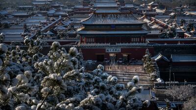 Snow on the rooftops as workers and security stand outside the Forbidden City before it opens the morning after a late spring snowfall on March 19, 2022 in Beijing. Getty Images