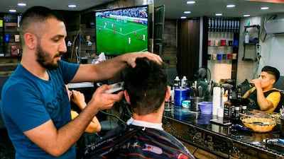 A barber cuts the hair of a Palestinian youth watching the World Cup 2022 Asian qualifying match. AFP