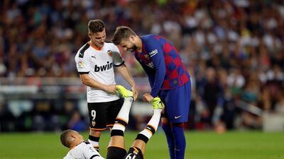 Barcelona's Gerard Pique helps Valencia's Kevin Gameiro stretch. EPA