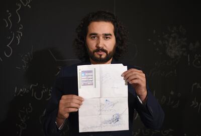 Omaid Sharifi, 32, poses for a picture as he holds his id card or Tazkira registered to vote in the upcoming parliamentary election, in Kabul. AFP