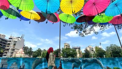 A city worker walks under an art installation of colourful umbrellas in Mumbai, India. AFP