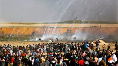 Palestinians run for cover from tears gas fired by the Israelis. Mohammed Abed / AFP