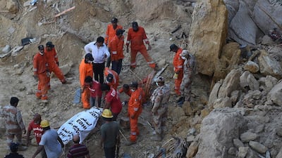 Pakistani rescuers move the body of a victim of a landslide in Karachi. Asif Hassan / AFP